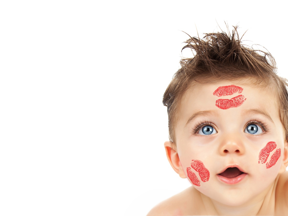 Маленький мальчик со следами от поцелуев на лице на белом фоне