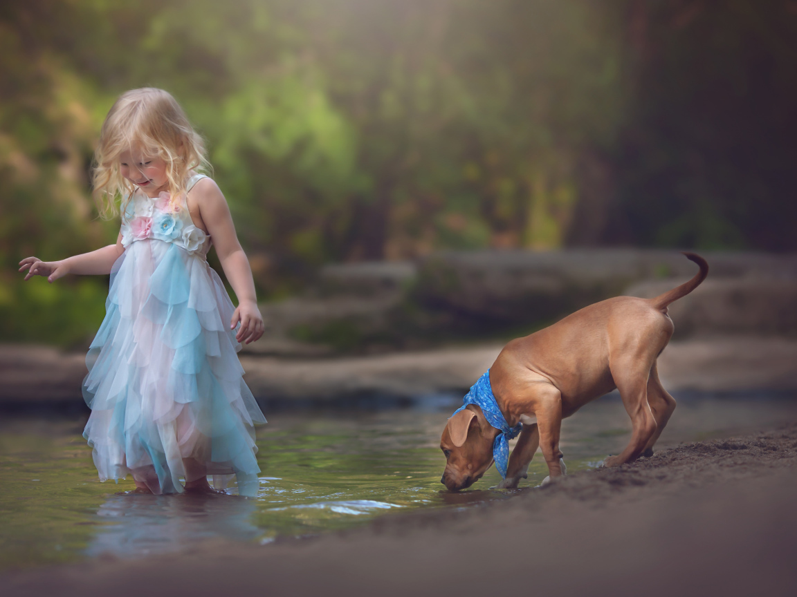 Маленькая девочка в красивом платье со щенком у ручья