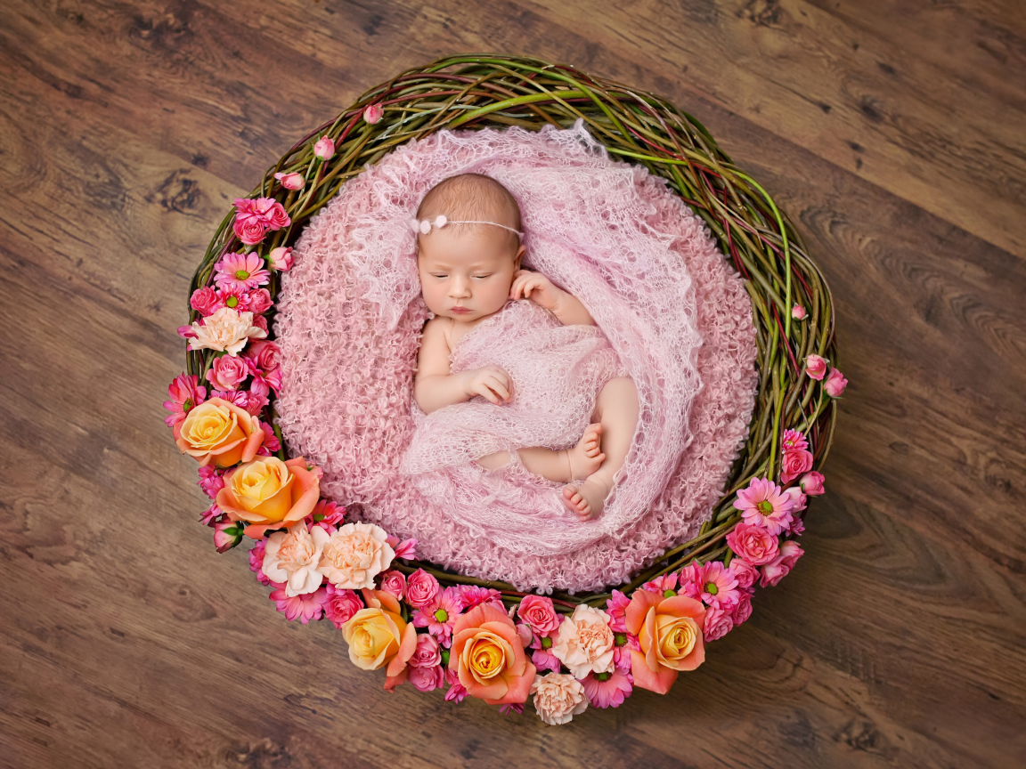 Маленькая девочка спит в корзине украшенной цветами