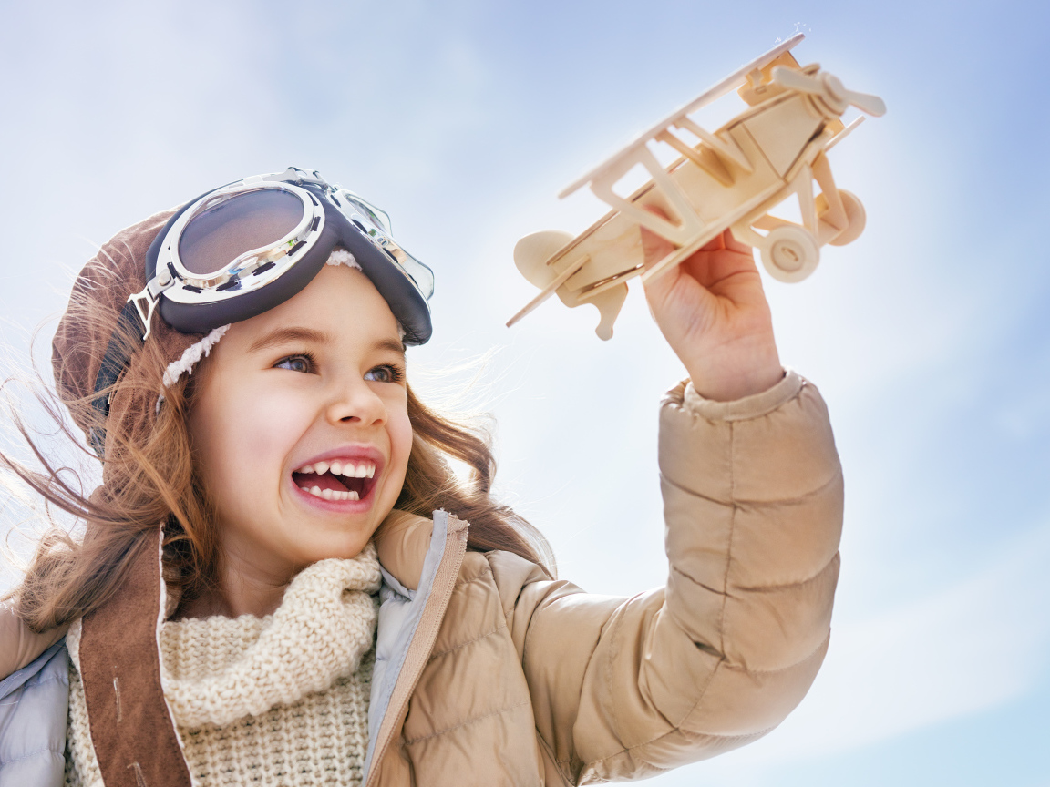 Маленькая улыбающаяся девочка с самолетом в руках 
