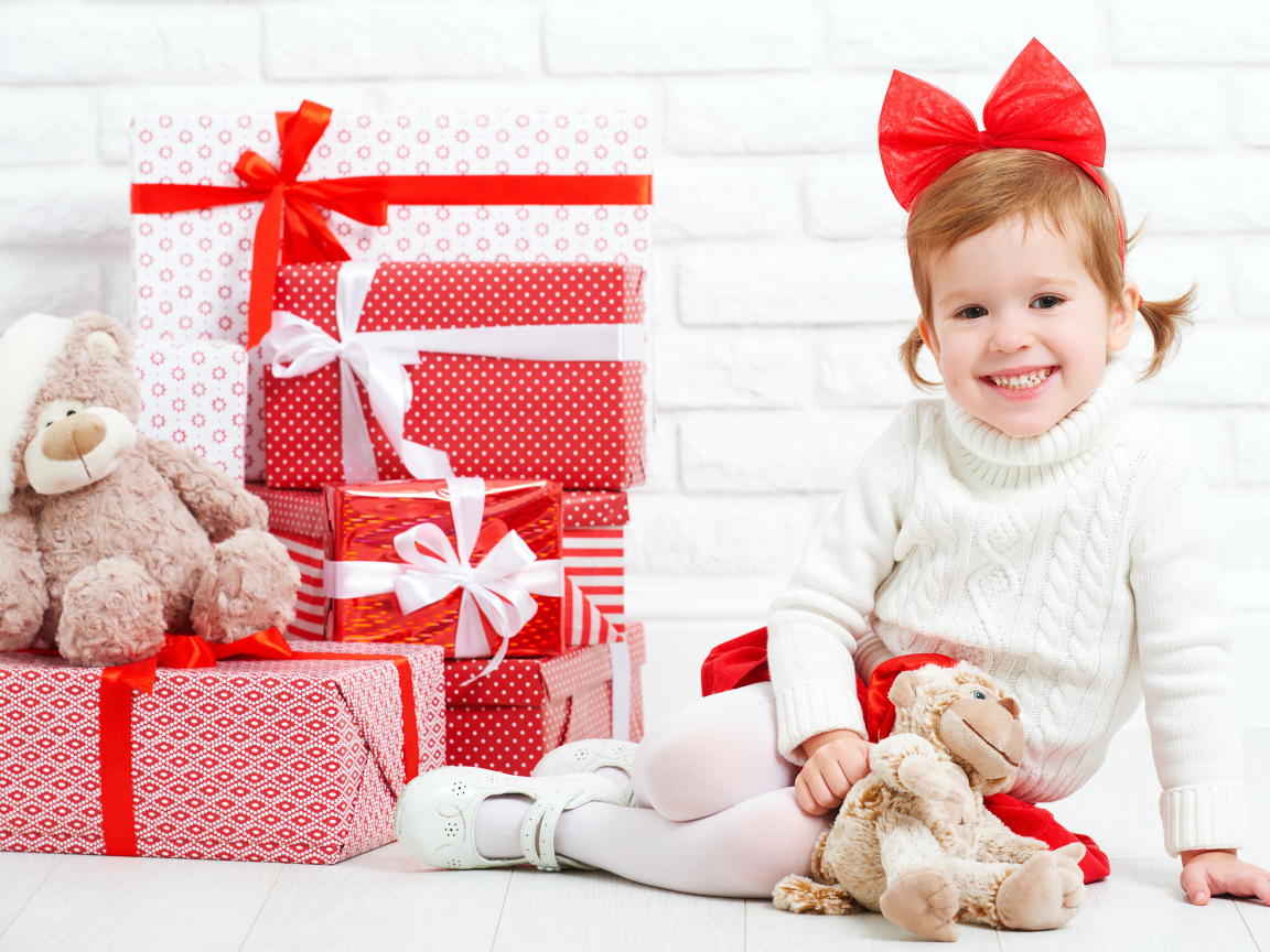 Маленькая улыбающаяся девочка с подарками на новый год