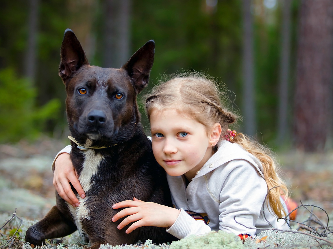 Милая голубоглазая девочка с большой черной собакой