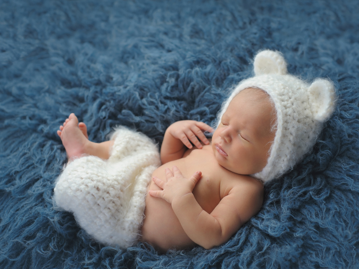 Спящий грудной ребенок в белом костюме медвежонка