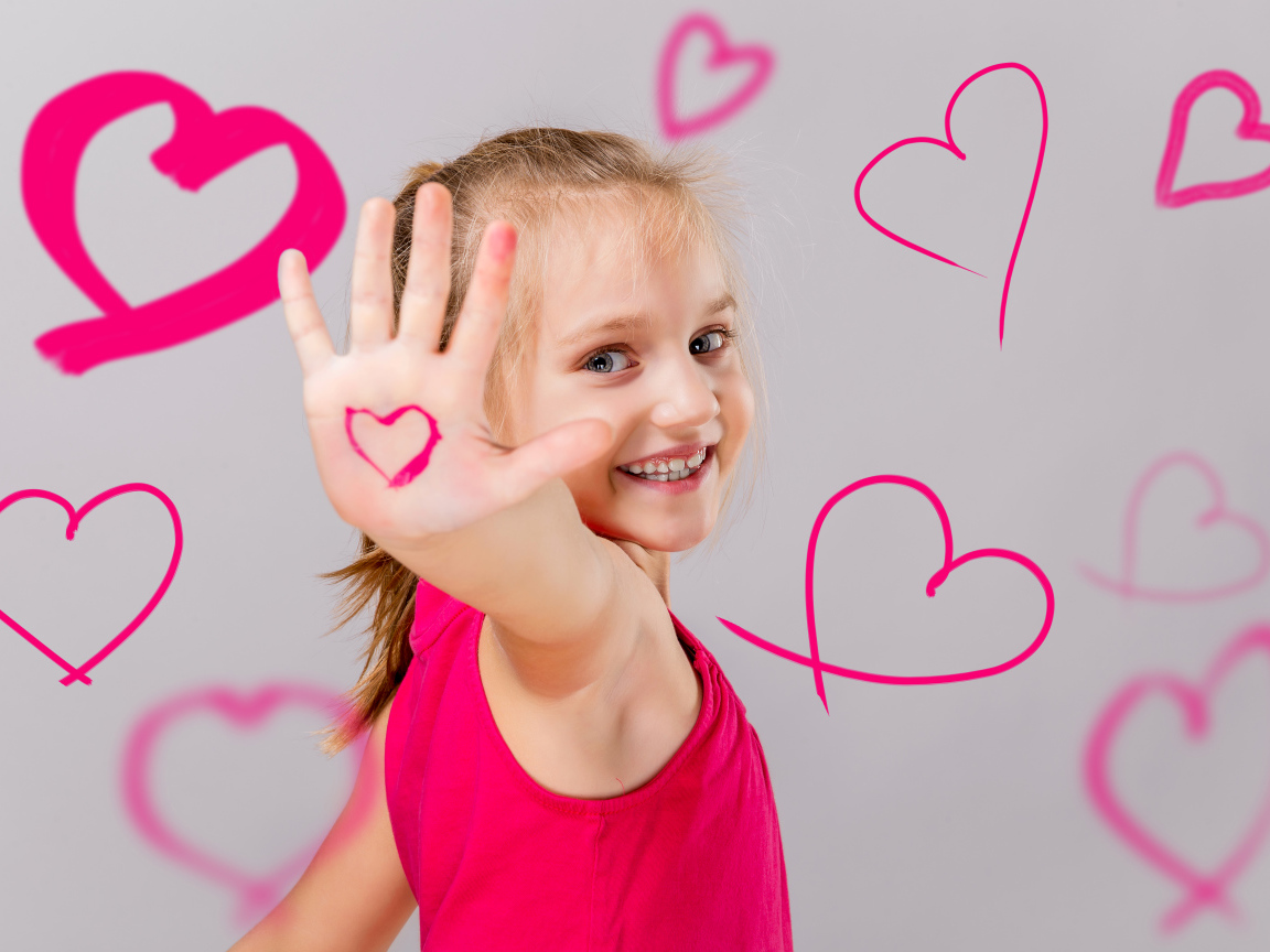 Улыбающаяся девочка с нарисованными сердечками на сером фоне