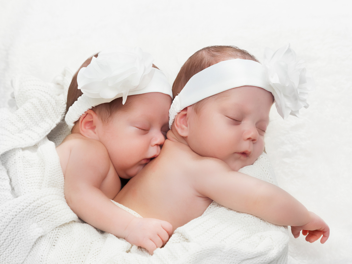 Два спящих младенца с большими белыми цветами на голове