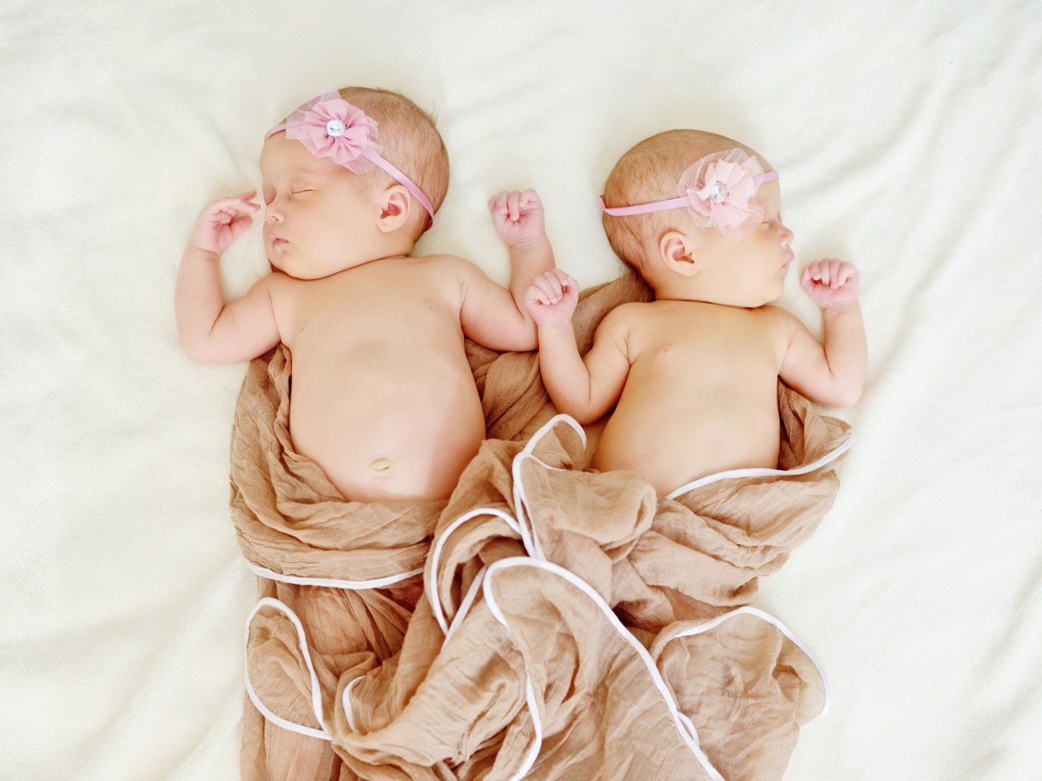 Два спящих младенца с розовыми цветами на голове