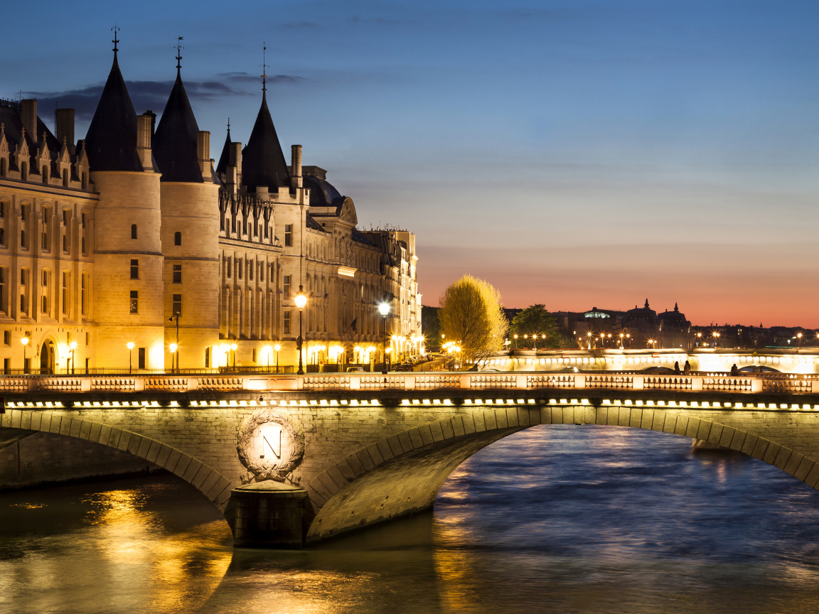 Мост в свете ночных фонарей у бывшего королевского замка Консьержери, Париж. Франция 