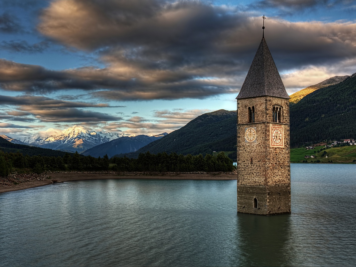 Старинная часовня на фоне красивого неба посреди озера Резия, Италия