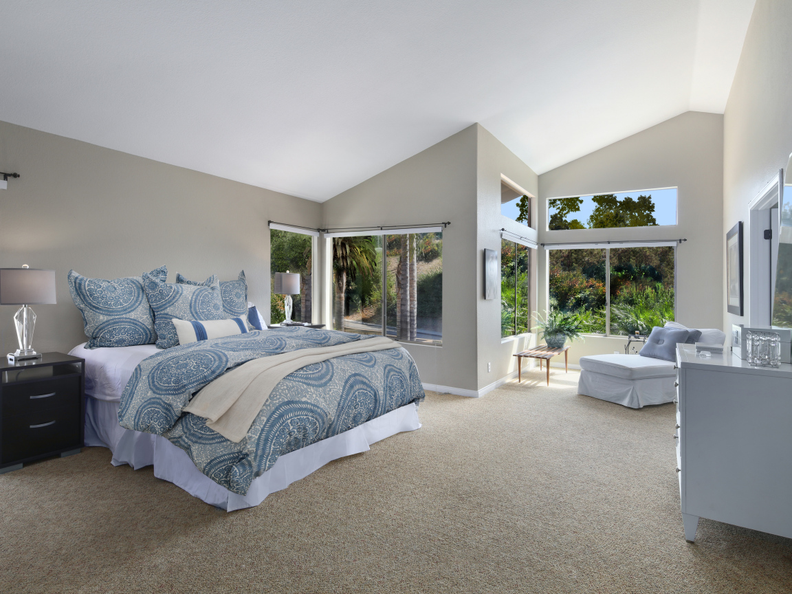 Уютная спальная комната в серых тонах с большими окнами