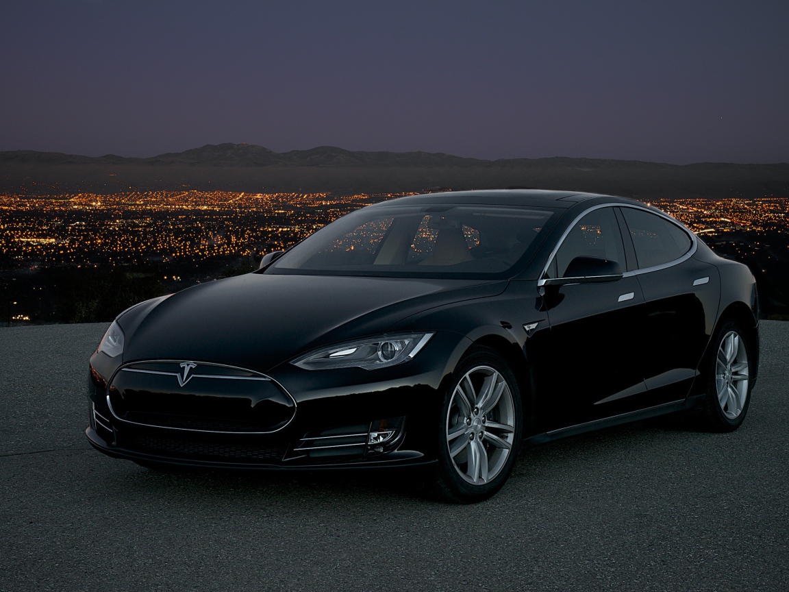 Черный стильный электромобиль Tesla Model S на фоне ночного мегаполиса 