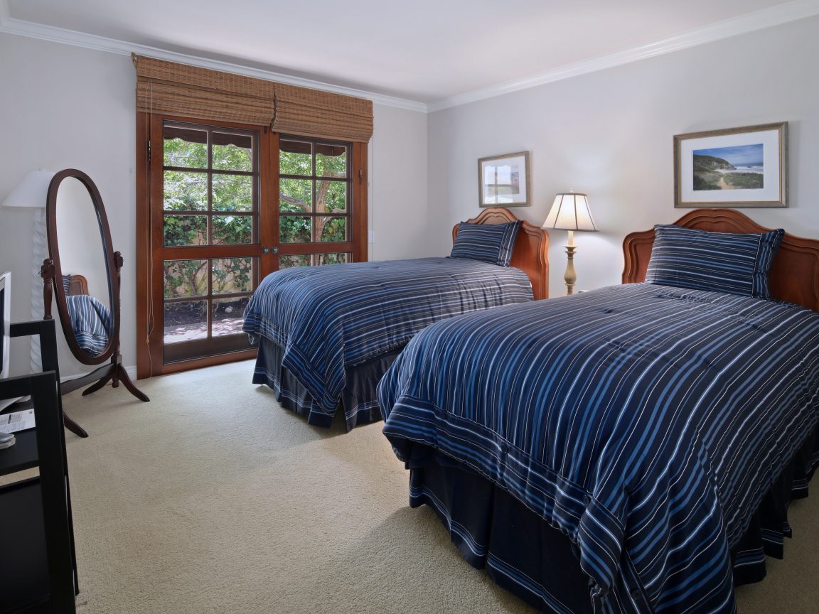 Две большие кровати в спальне с деревянным окном