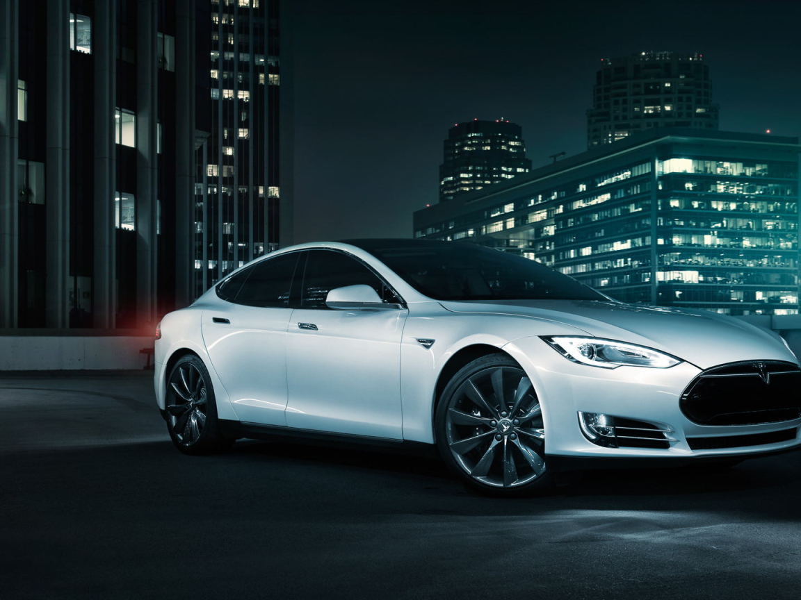 Белый электромобиль Тесла на фоне города 