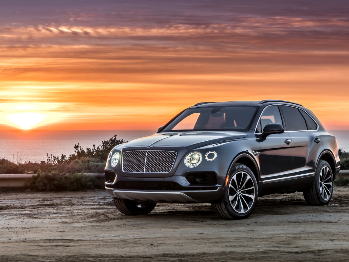 Черный стильный стильный автомобиль Bentley на фоне заката 