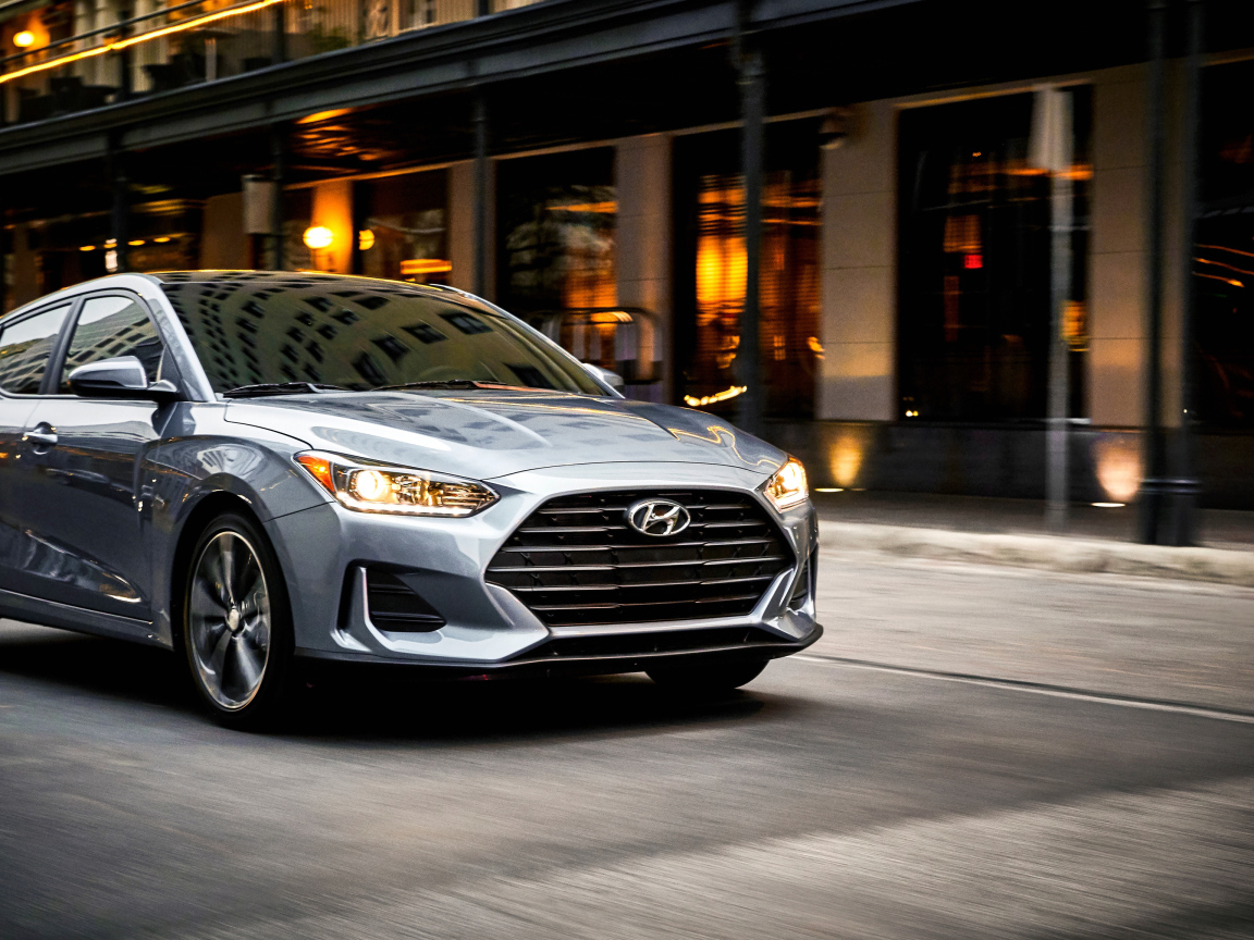 Серебристый автомобиль Hyundai Veloster, 2019 с  включенными фарами 