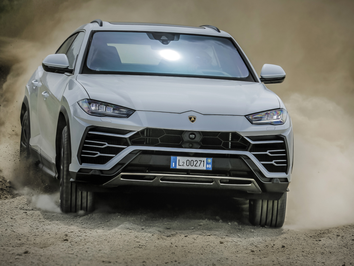 Белый автомобиль Lamborghini Urus  2018 года едет по дороге 