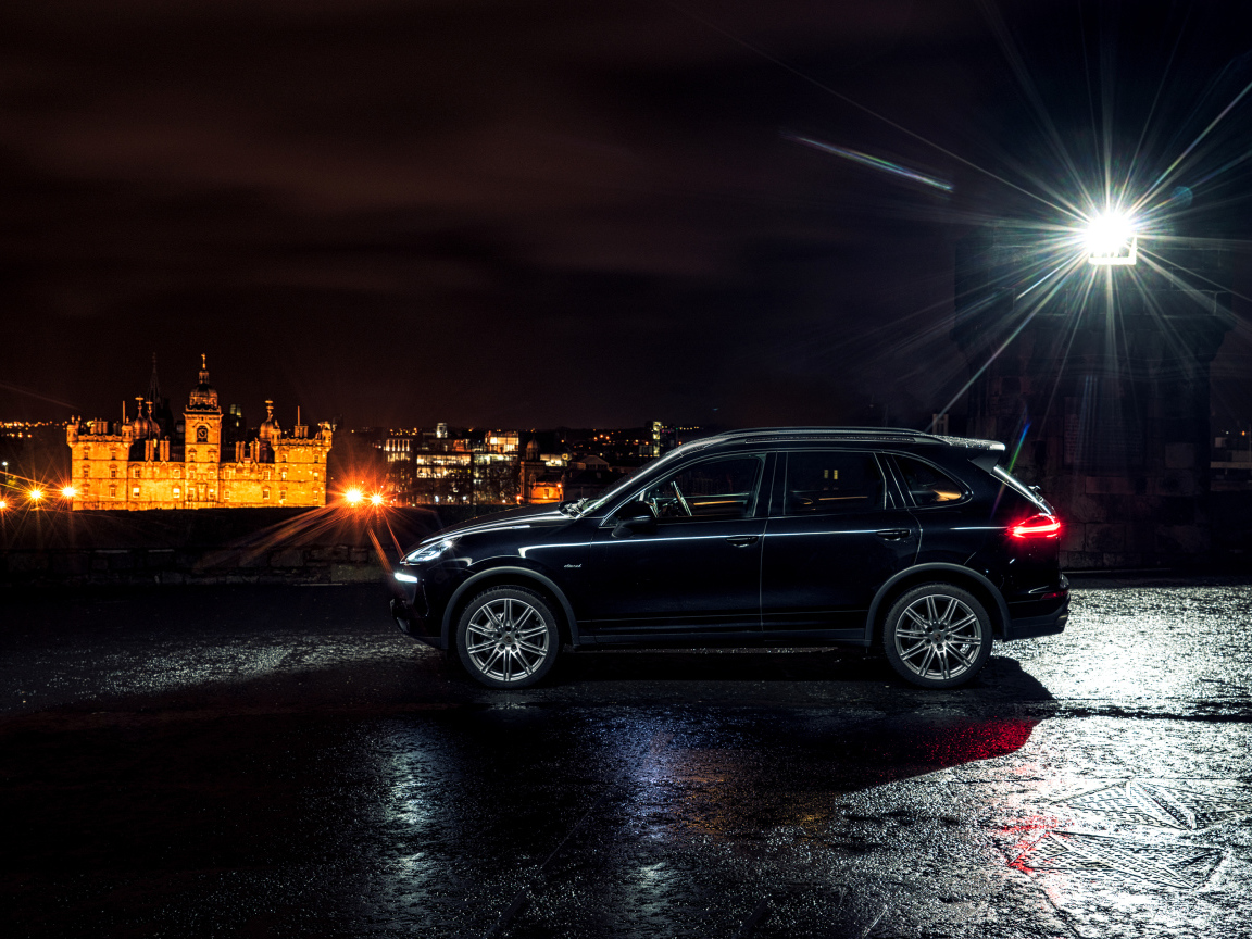 Черный автомобиль Porsche Cayenne в свете фонаря 