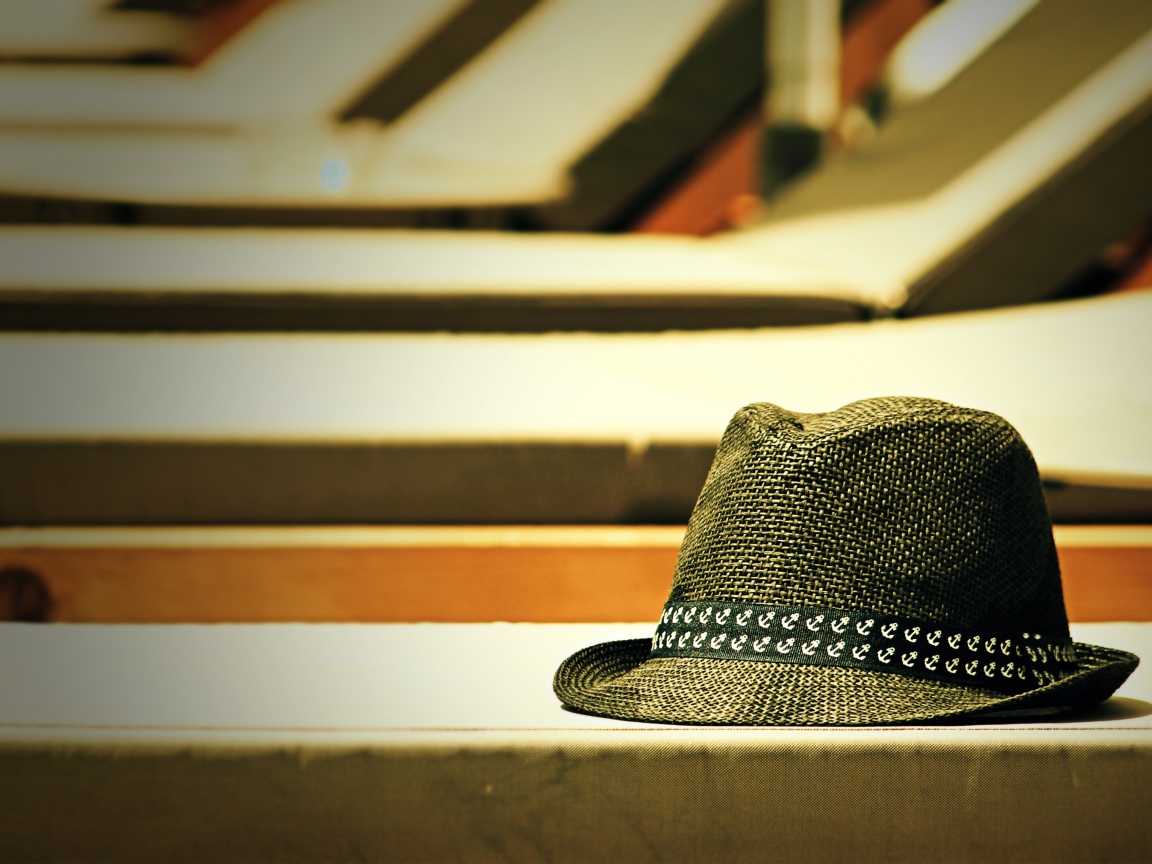 Летняя шляпа лежит на лавке в лучах солнца