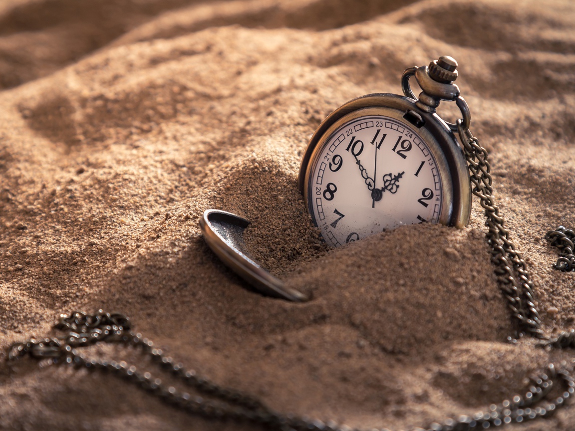 Pocket watch on a chain in the sand