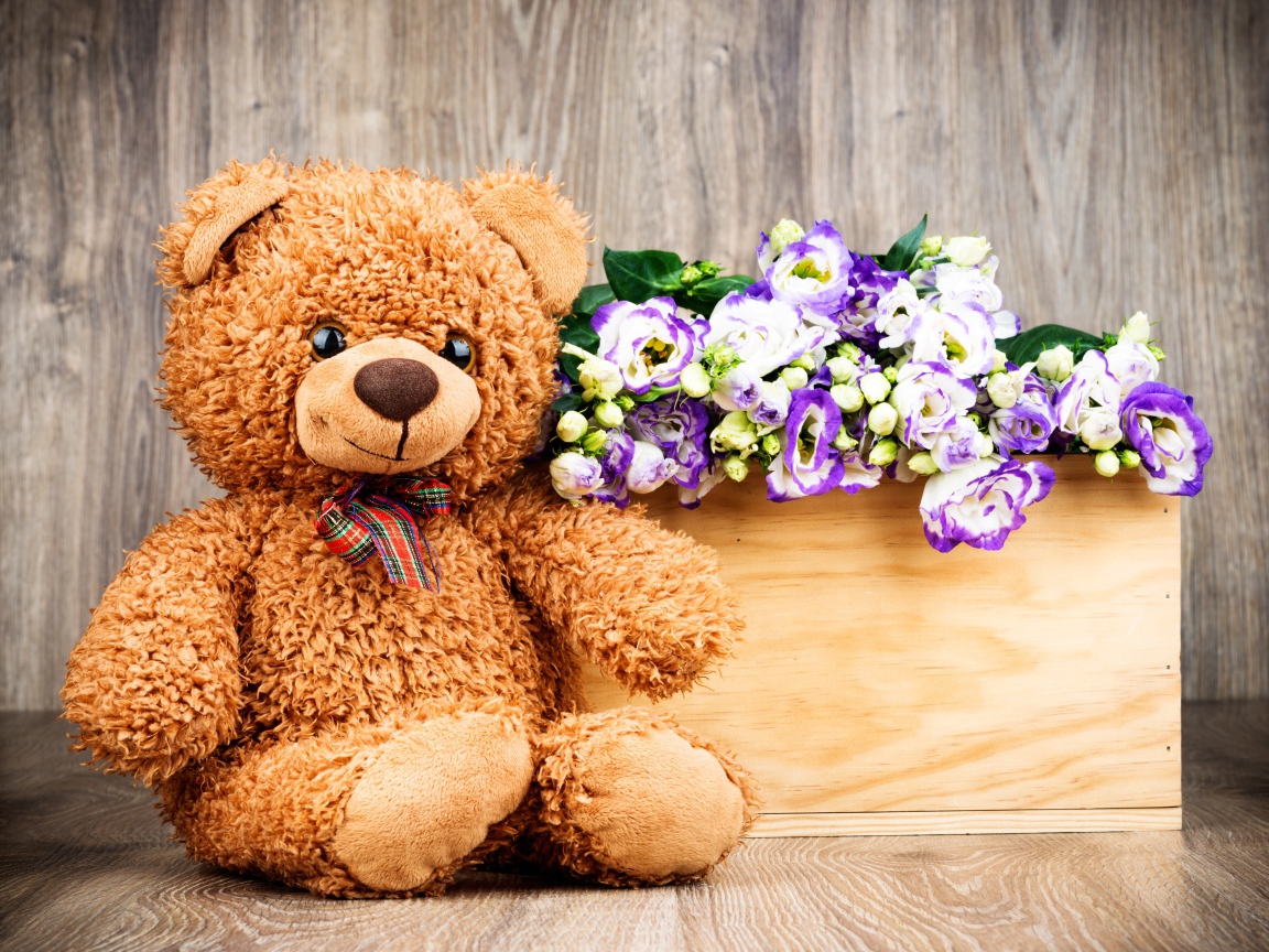 Плюшевый мишка с букетом цветов на деревянном фоне