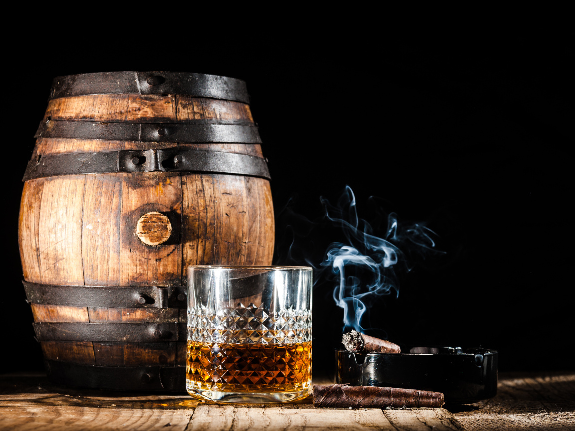 A keg of rum, with a glass of whiskey and a cigar on a black background