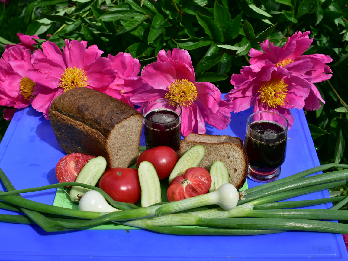 Черный хлеб, овощи и вино на фоне розовых пионов 