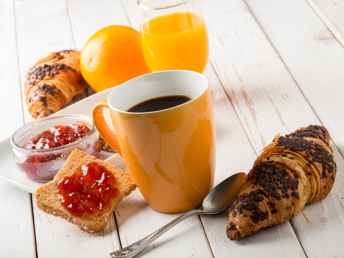 Кофе на деревянном столе с круассанами, соком и джемом 