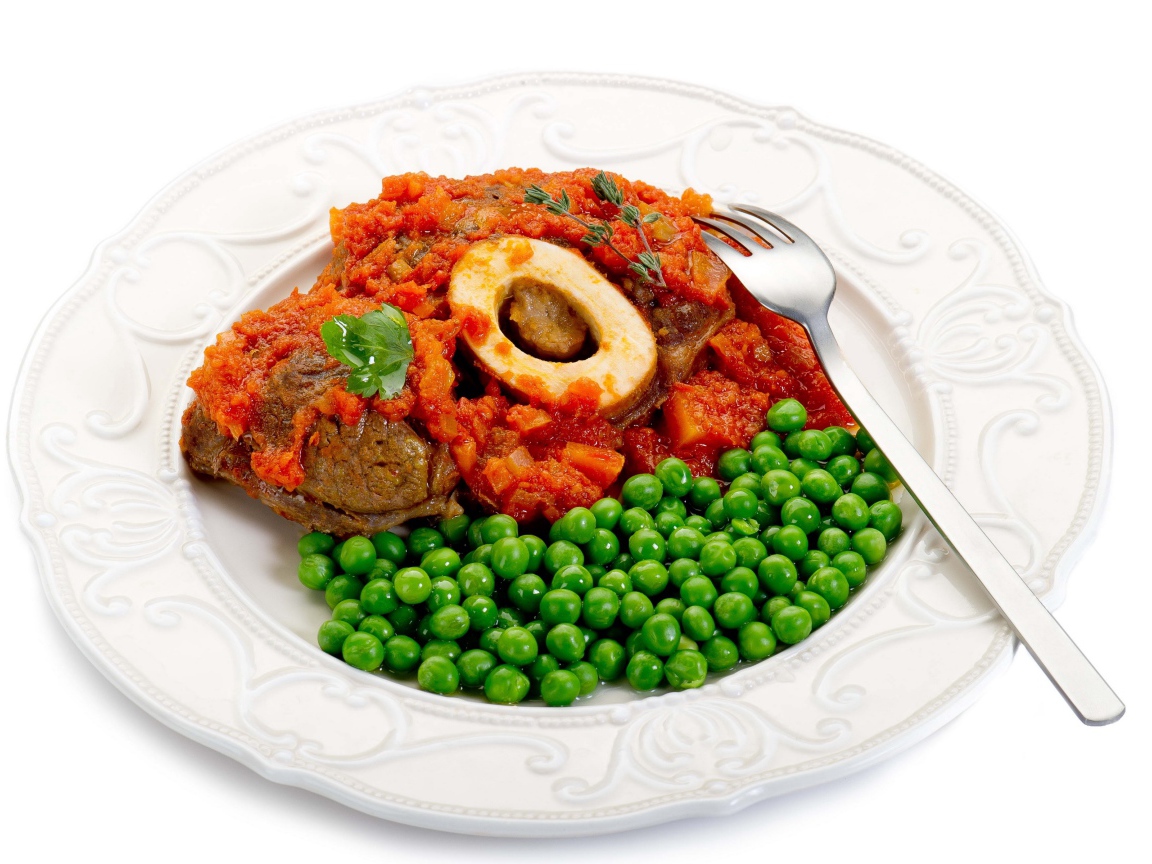 Зеленый горошек на белой тарелке с мясом