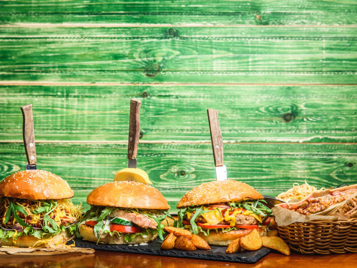 Гамбургеры с ножами на деревянном фоне