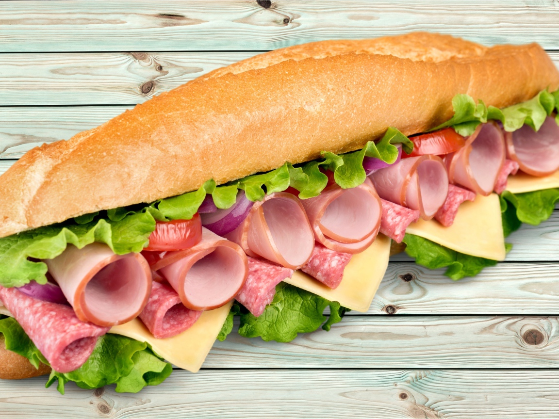 Большой бутерброд с колбасой, сыром и листьями салата