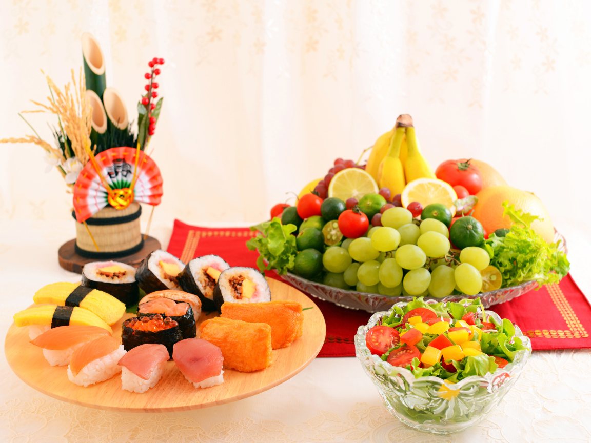 Роллы на столе с овощным салатом и фруктами 