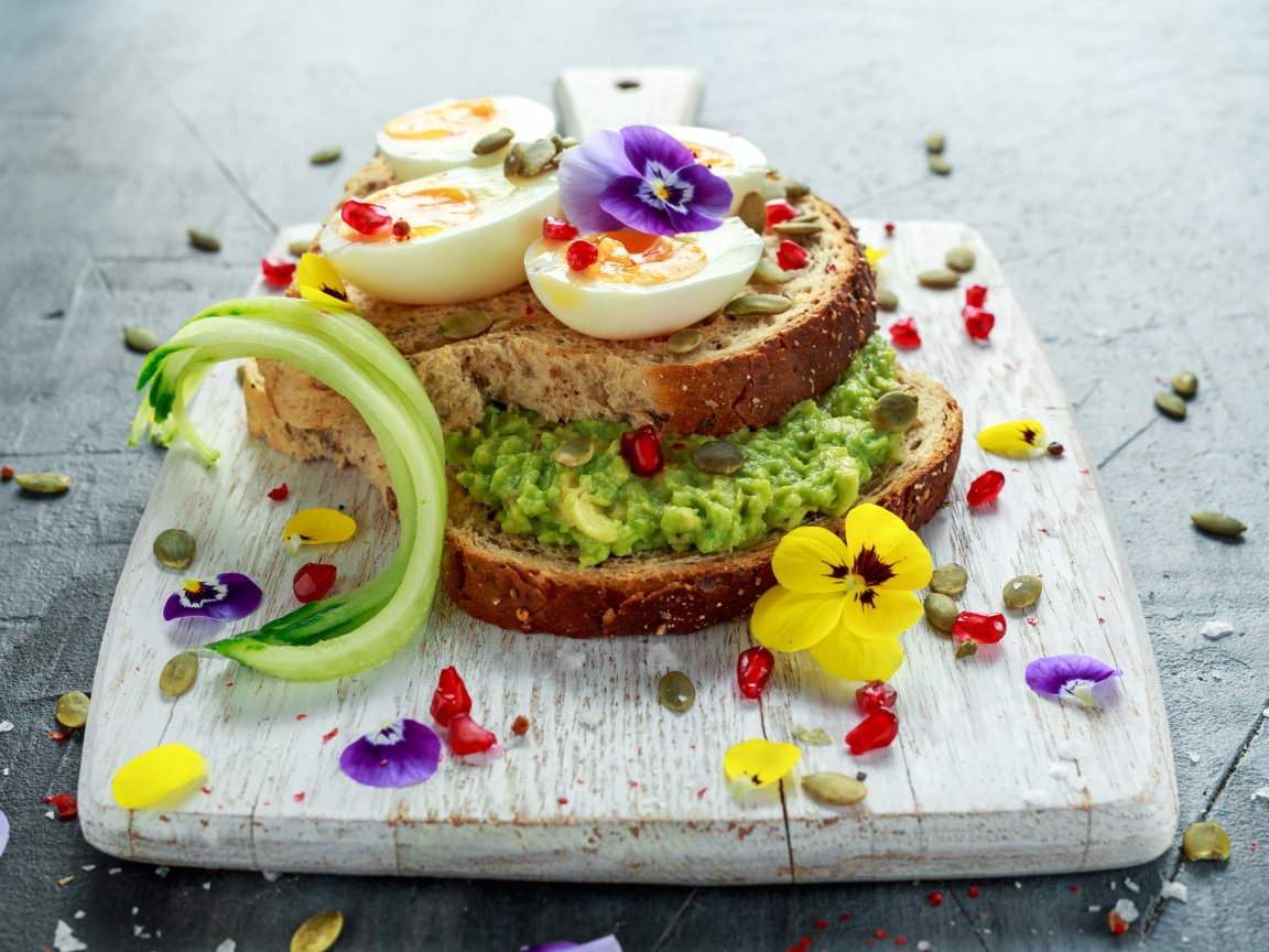 Сендвич с яйцом и цветами на доске