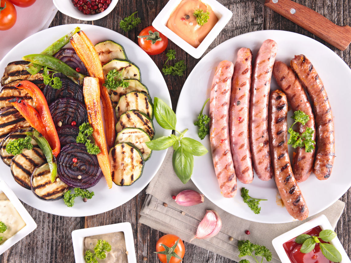 Овощи и сосиски гриль на столе с соусом