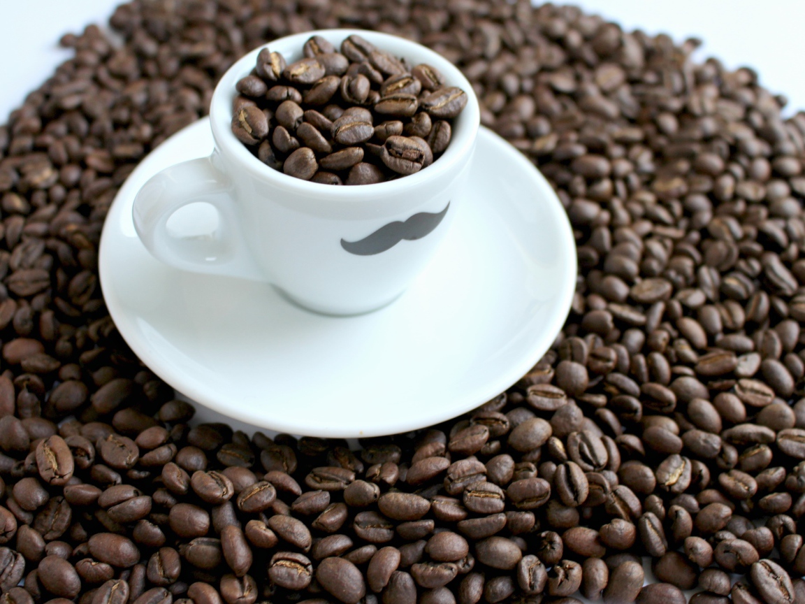 Белая чашка с жареными кофейными зернами стоит на столе с кофейными зернами