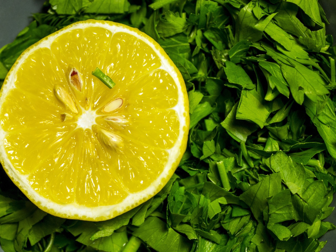 Половина желтого лимона с нарезанной зеленью петрушки 