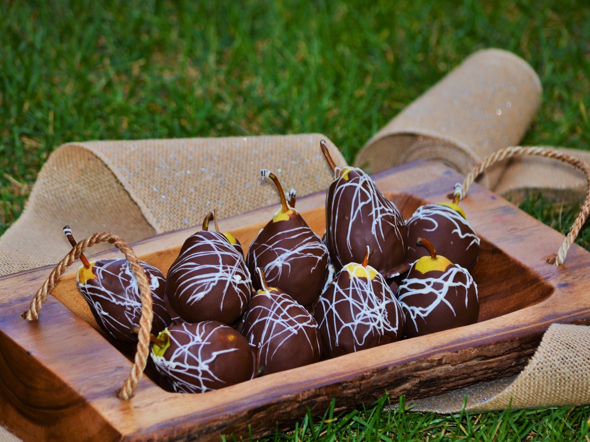 Груши в шоколадной глазури стоят на зеленой траве