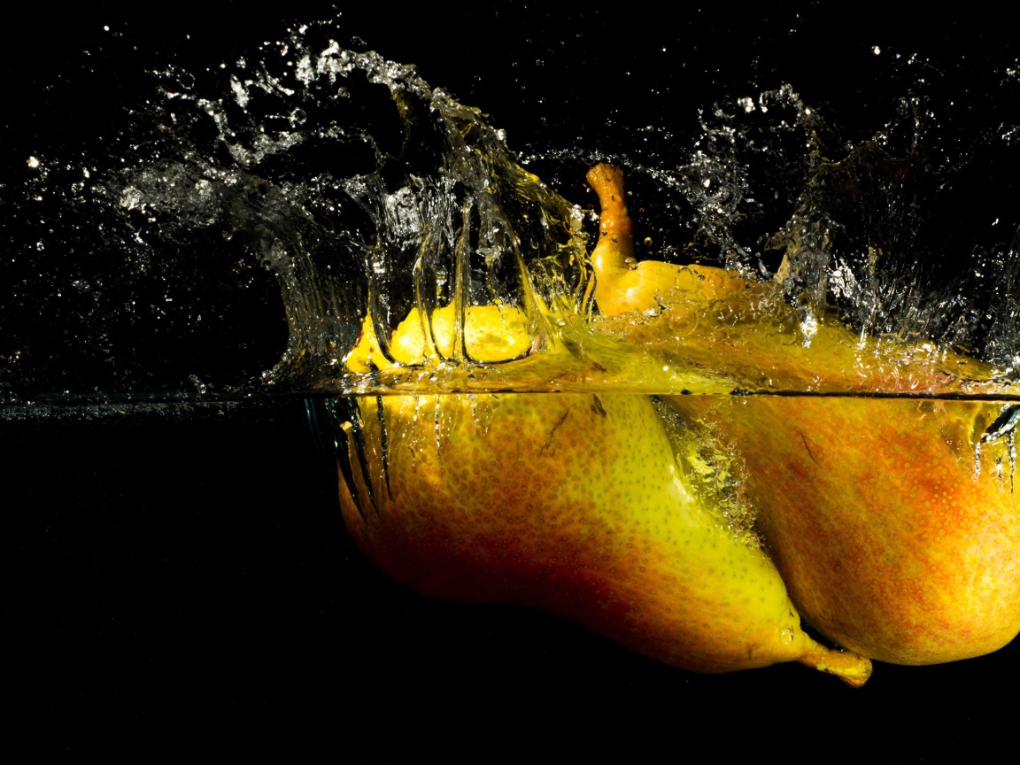 Груши в воде с брызгами на черном фоне