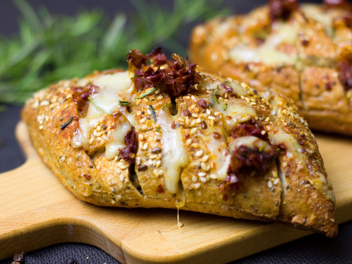 Булочка с кунжутом и сыром на разделочной доске 