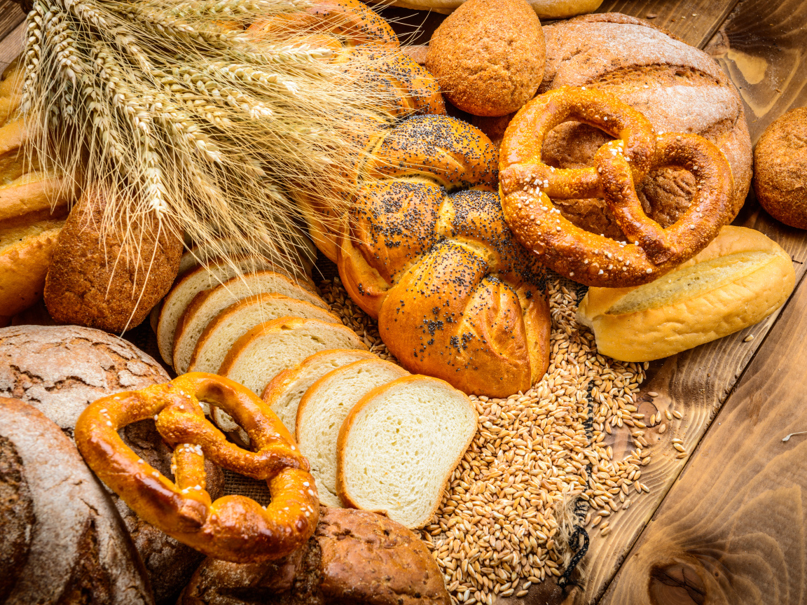 Свежая выпечка с колосьями и зернами пшеницы на столе 