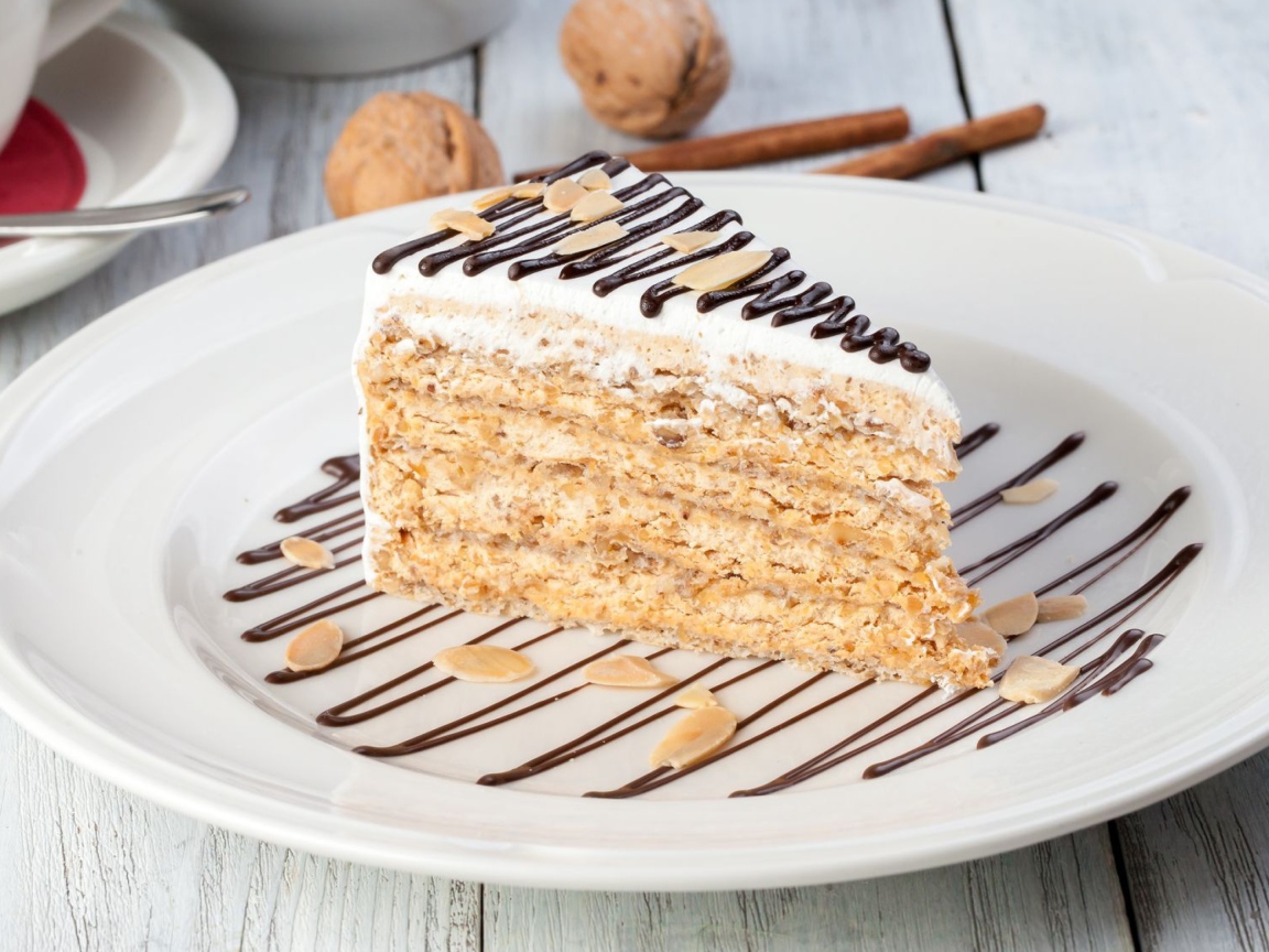 Кусок торта с орехами и шоколадом на белой тарелке