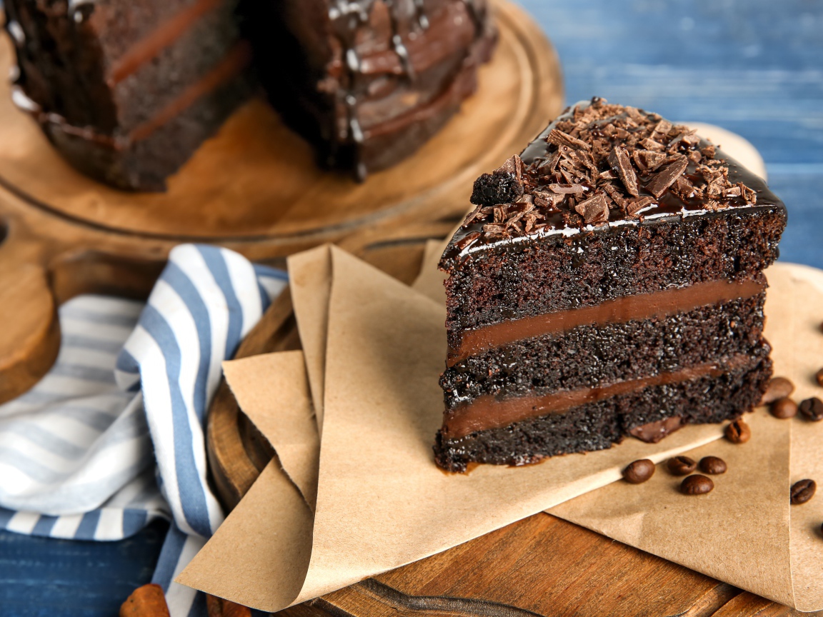 Кусок вкусного шоколадного торта на столе с кофейными зернами