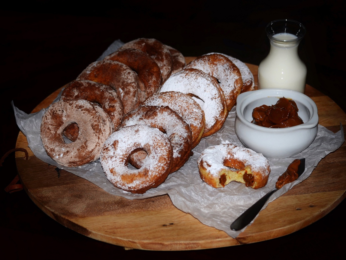 Аппетитные пончики со сгущенкой и свежим молоком на столе