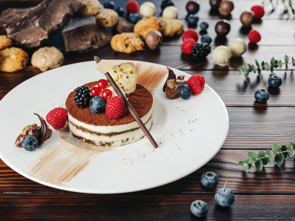 Пирожное с ягодами и шоколадом на белой тарелке 