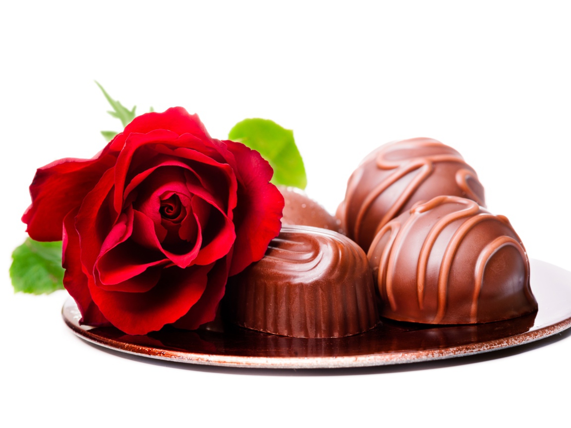 Шоколадные конфеты на тарелке с красной розой на белом фоне