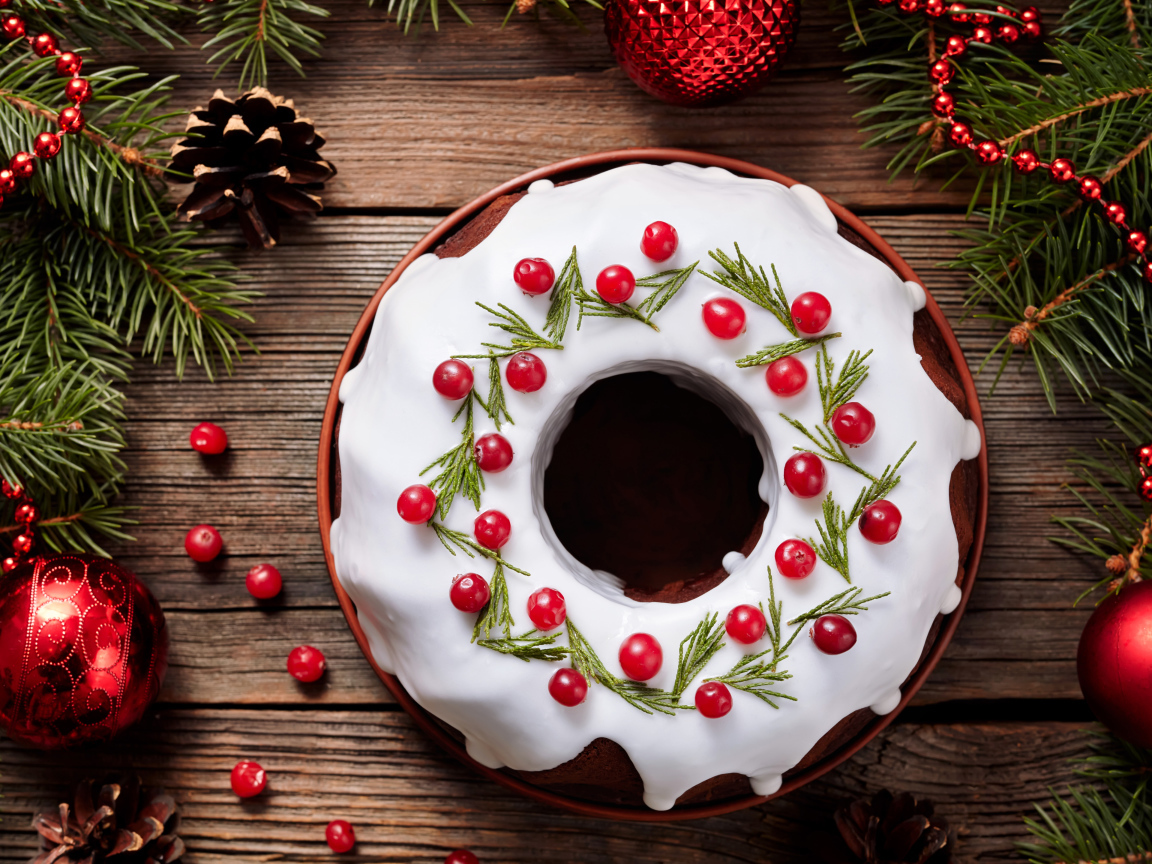 Рождественский пирог с ягодами клюквы на деревянном столе с еловыми ветками