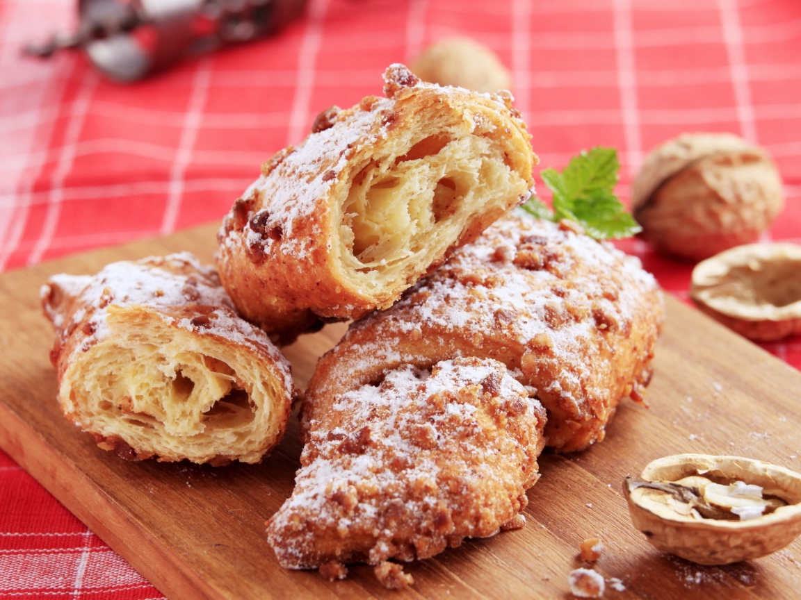 Круассаны с орехом и сахарной пудрой на разделочной доске