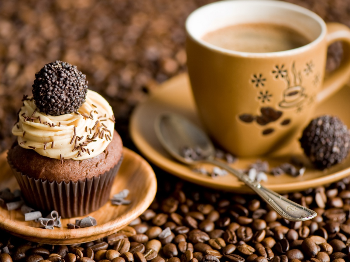 Кекс с кремом и чашкой кофе стоят на кофейных зернах 