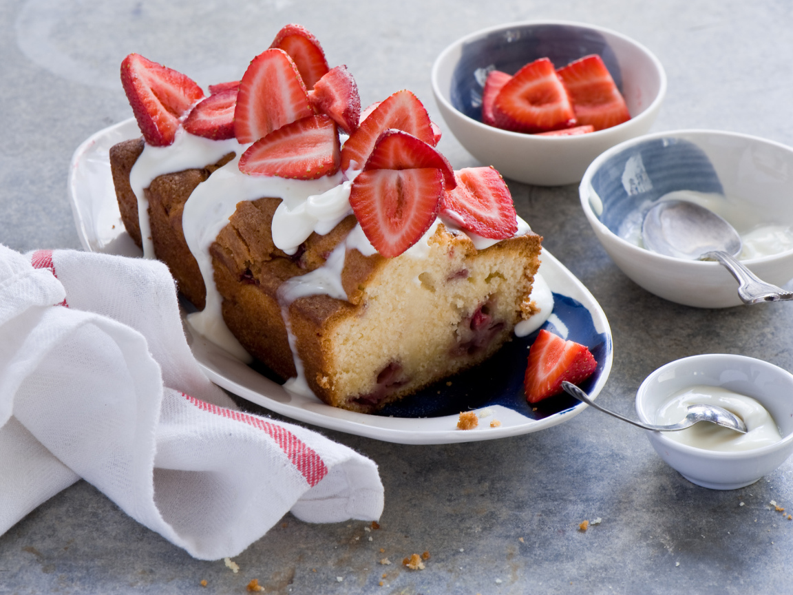 Кекс с кремом на тарелке со свежей клубникой 