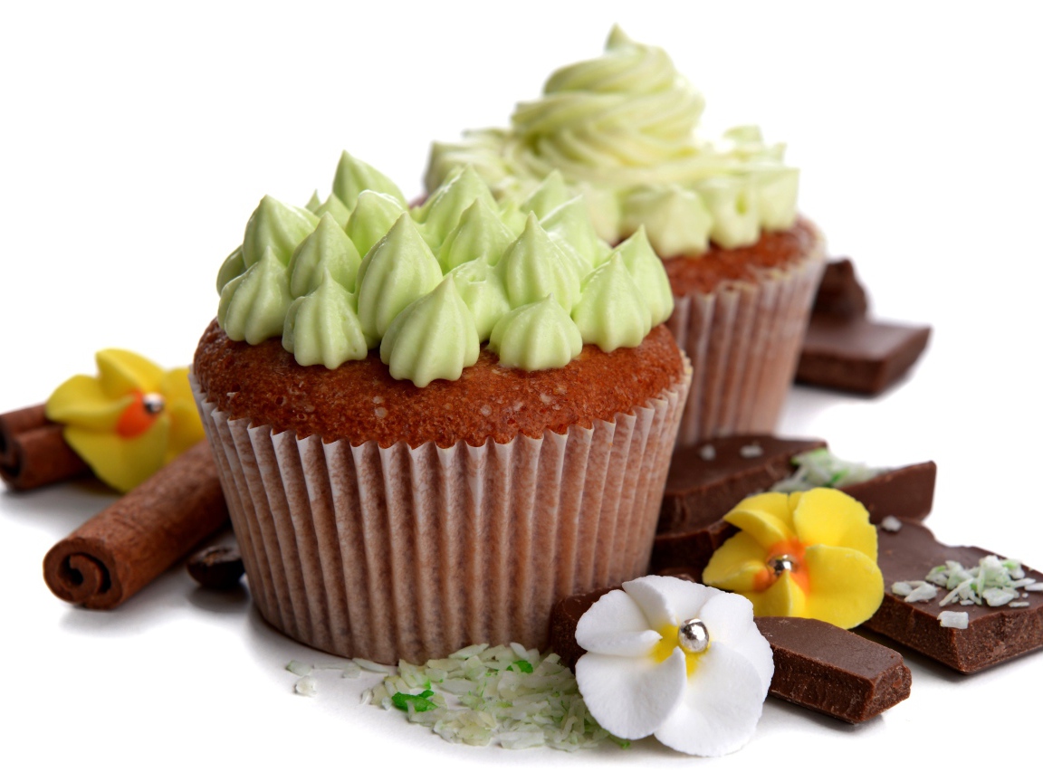 Кексы с кремом, шоколадом и корицей на белом фоне