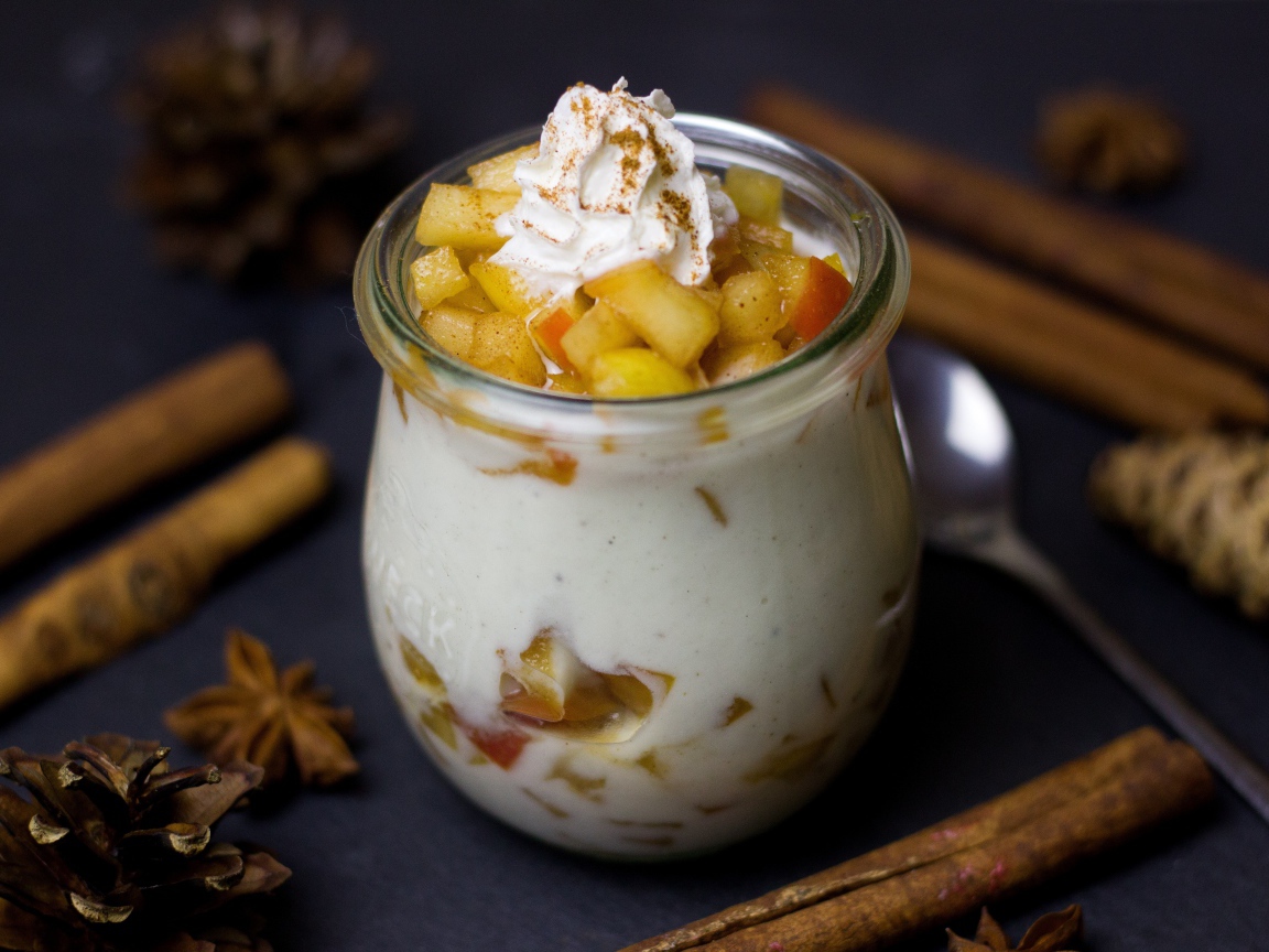 Десерт из йогурта с фруктами на столе с пряностями