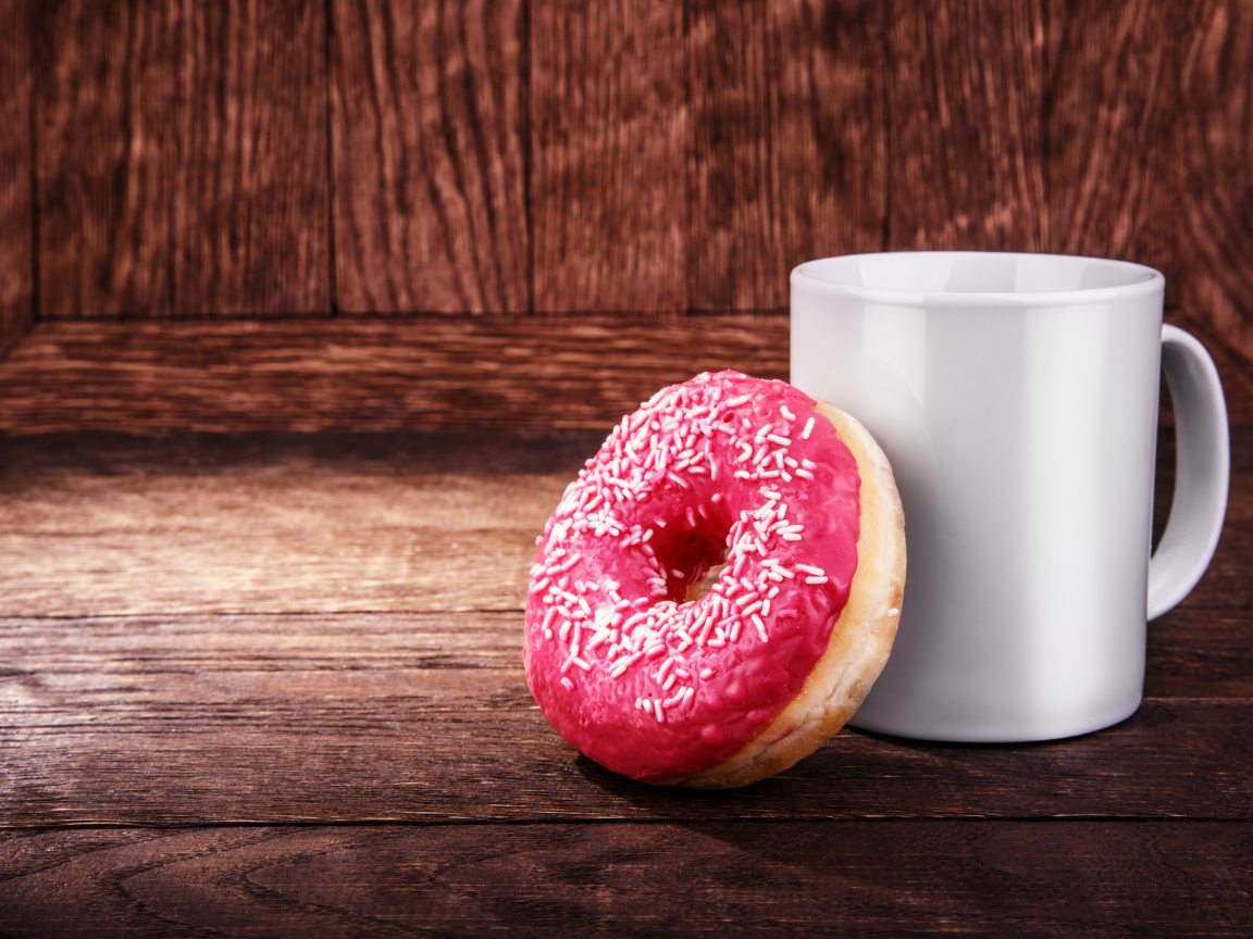 Пончик с белой кружкой на деревянном столе